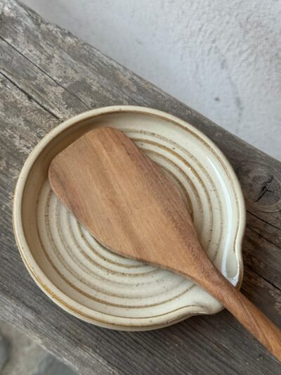Ronde lepelhouder uit beige klei met een houten spatel erin