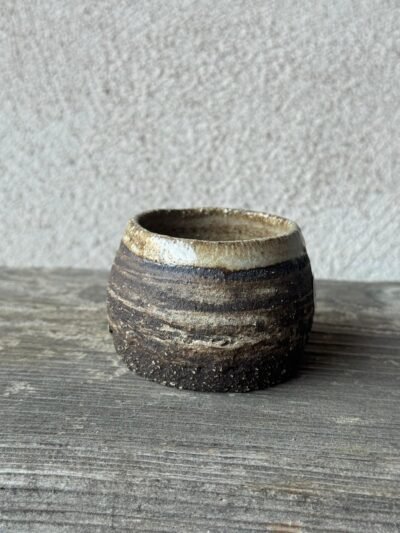 Kleine handgemaakte espressokop uit donkere klei met een lichte bovenrand