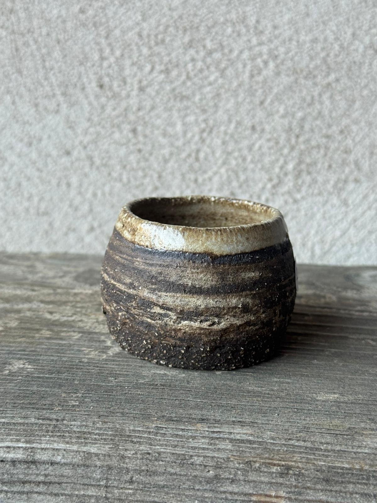 Kleine handgemaakte espressokop uit donkere klei met een lichte bovenrand