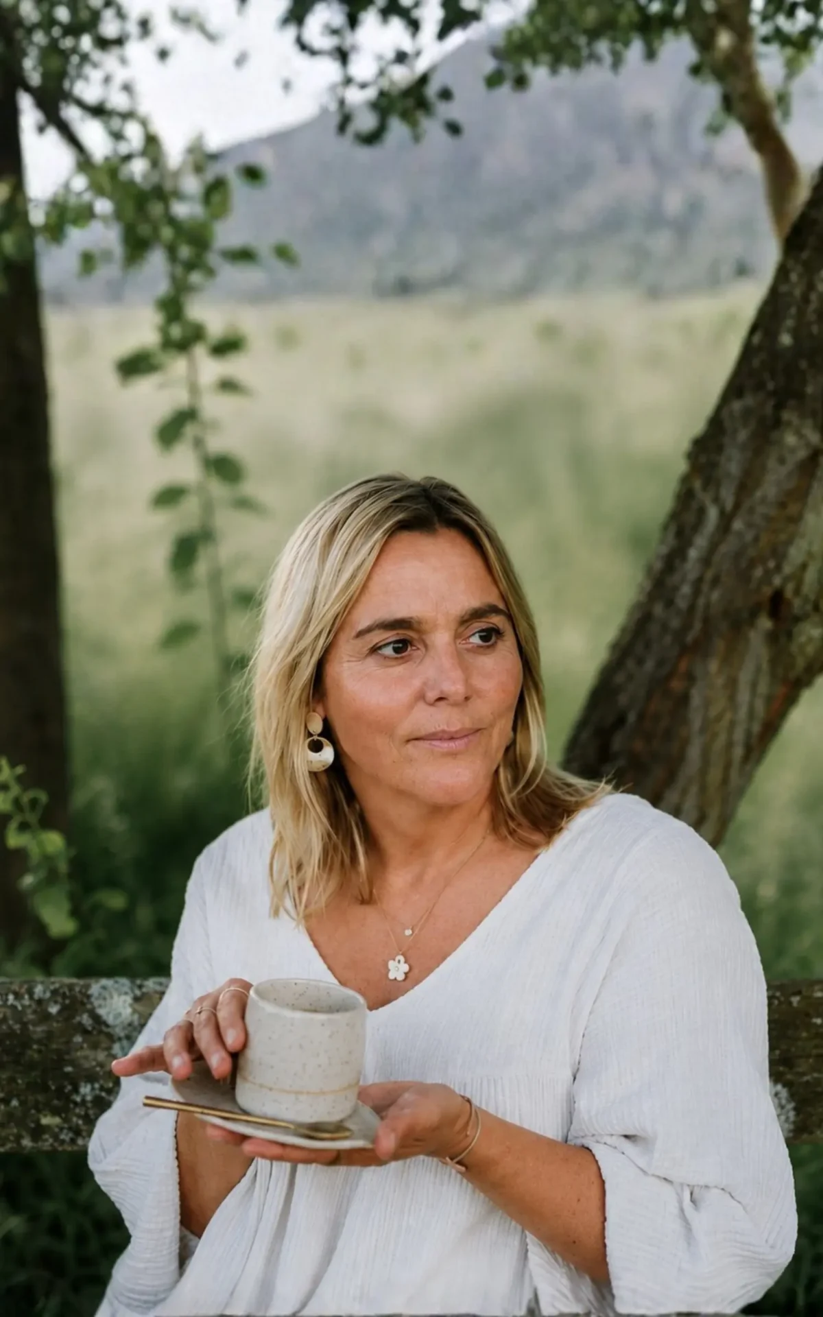 Vanessa buiten bij het atelier, met een handgemaakte keramieken kop in haar handen.